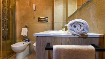 Ein modernes Badezimmer mit einer Bidet, Toilette und Waschbecken mit Handtuch auf der Ablagefläche.