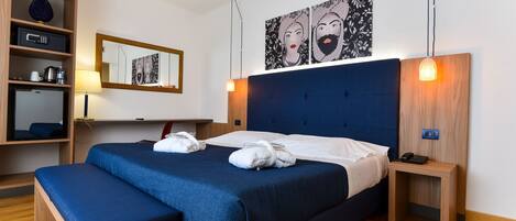 Una habitación de hotel moderna con una cama grande, mesitas de noche, un armario y obras de arte en las paredes.