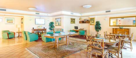Un salón amplio con una gran mesa de comedor, numerosas sillas y diversas opciones de asiento, incluyendo sofás y sillones.