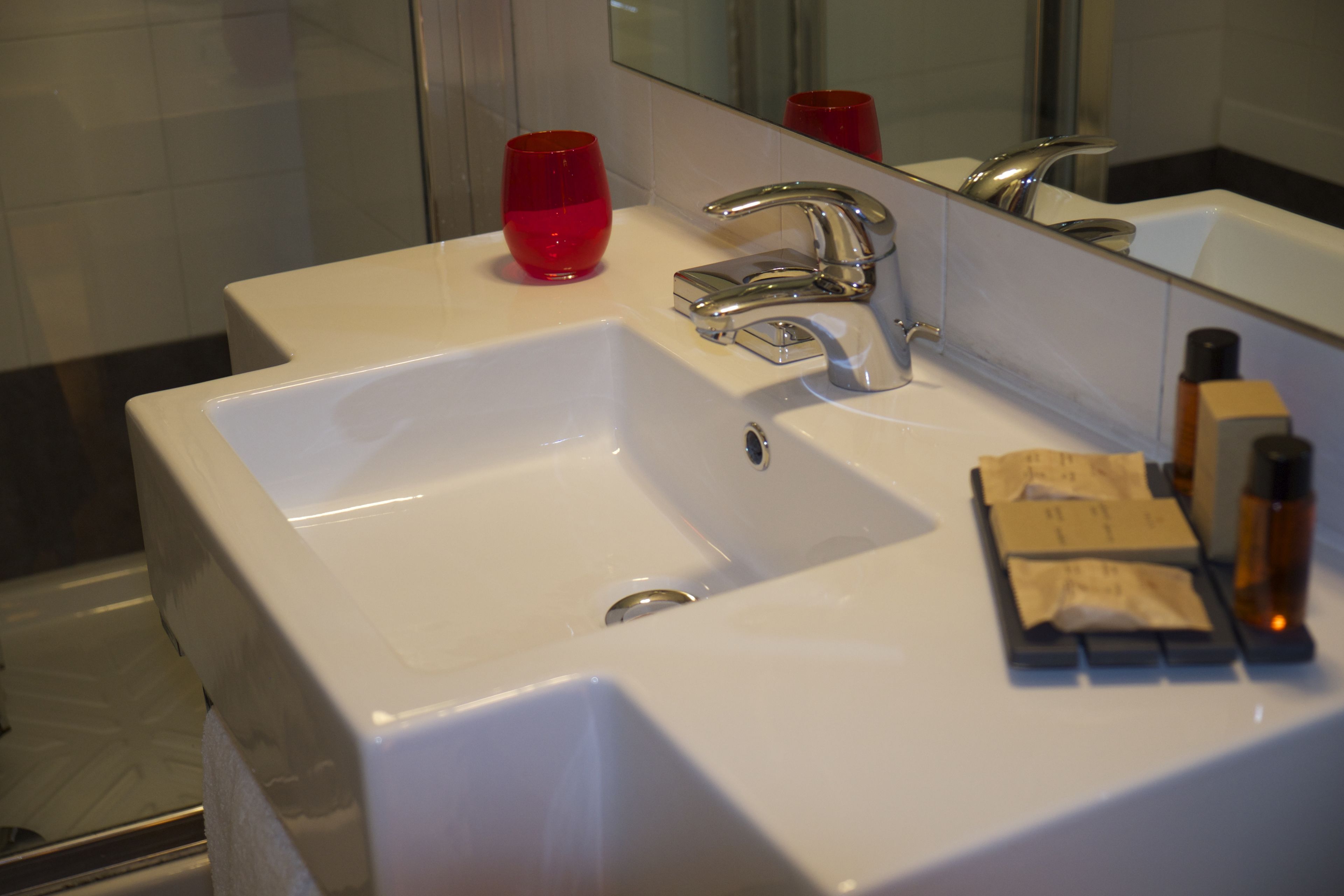 A bathroom sink with a mirror, a red cup, and toiletries.
