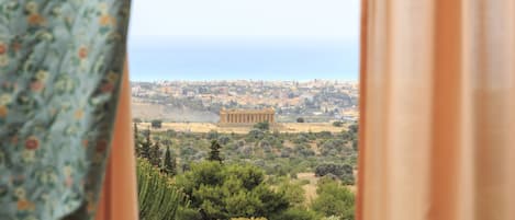 A view of the Acropolis with the Parthenon in the background, viewed through a window with curtains.