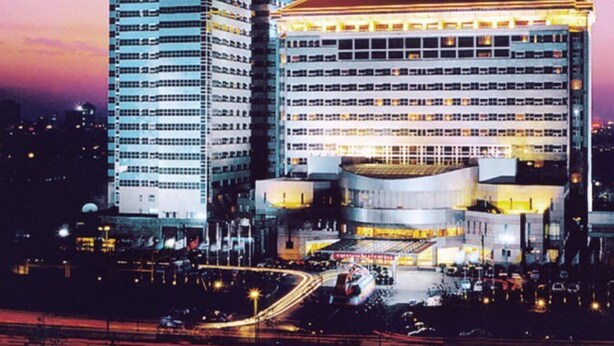 Un immeuble de grande hauteur au design moderne, comprenant de nombreux étages et un hall d’entrée imposant.