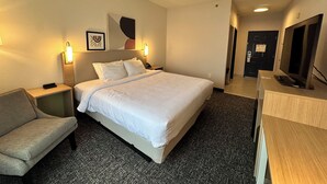 A hotel room with a bed, a desk, a chair, a TV, and a door. - Spark by Hilton Guilford (Guilford)