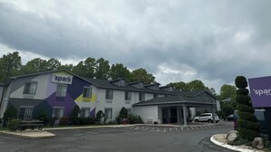 A hotel with a 'spark by Hilton' sign, a parking lot, and a covered parking area. - Spark by Hilton Guilford (Guilford)