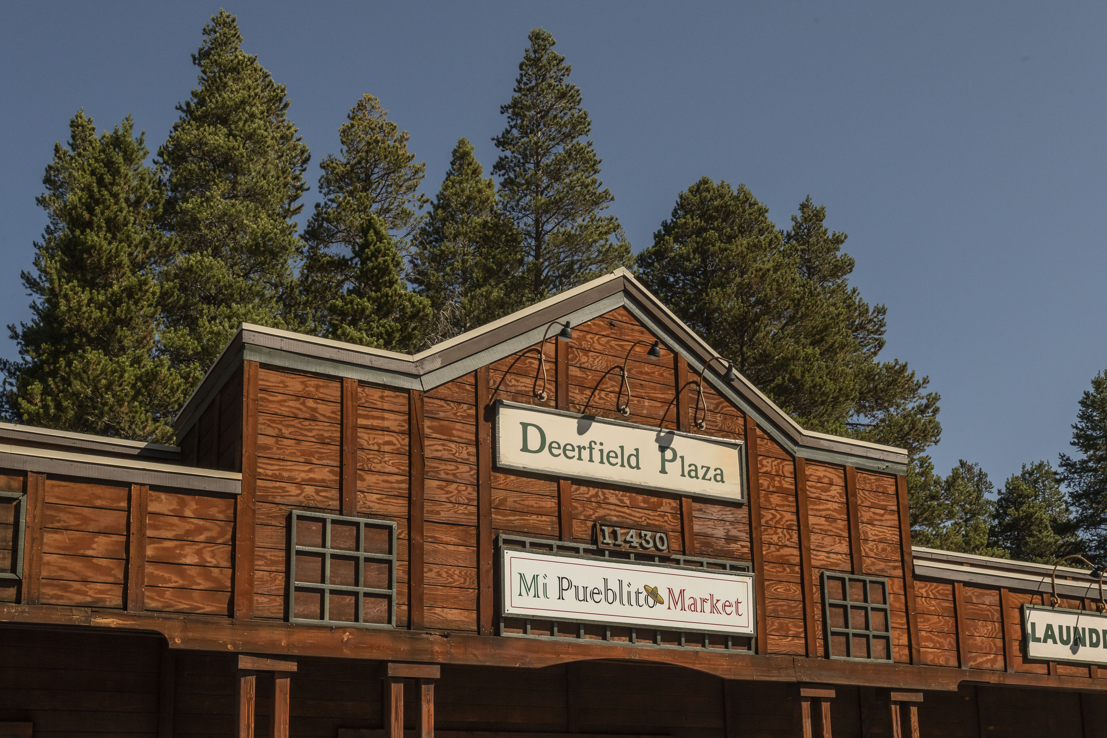 Un edifici de fusta amb indicadors que mostren 'Deerfield Plaza' i 'Mi Pueblo Market'.