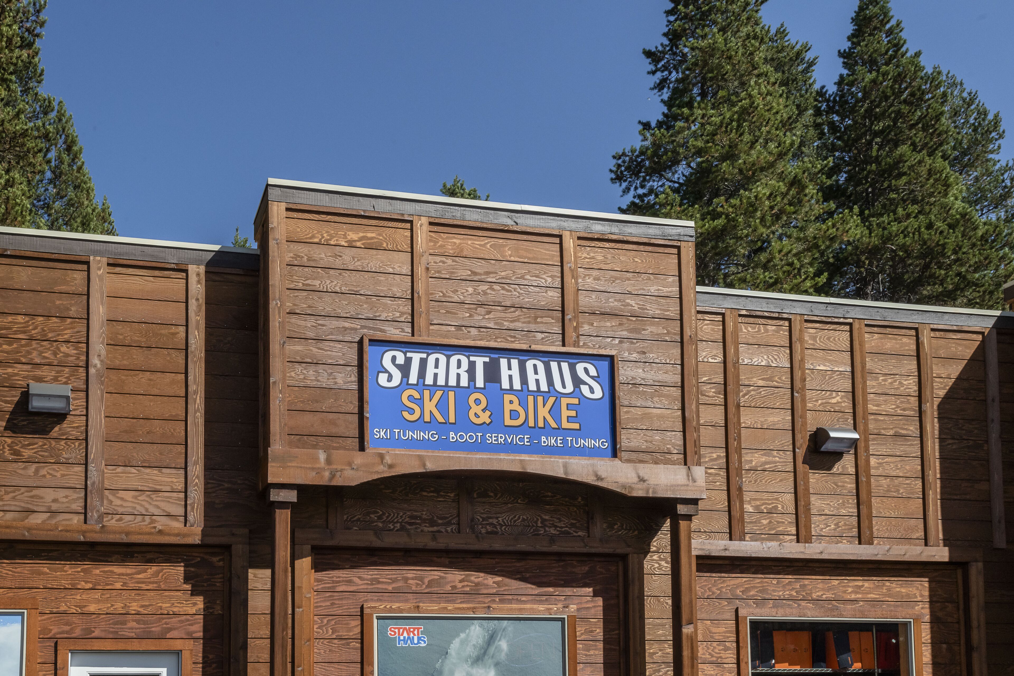 A wooden building with a sign that reads "Start Haus Ski & Bike" offering ski tuning, boot service, and bike tuning.