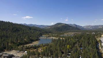 A mountainous landscape with a lake, dense forest, and several buildings.