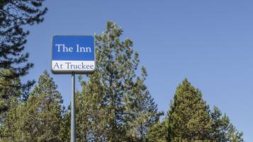 Señal de 'The Inn At Truckee' con un cielo azul despejado y pinos al fondo.