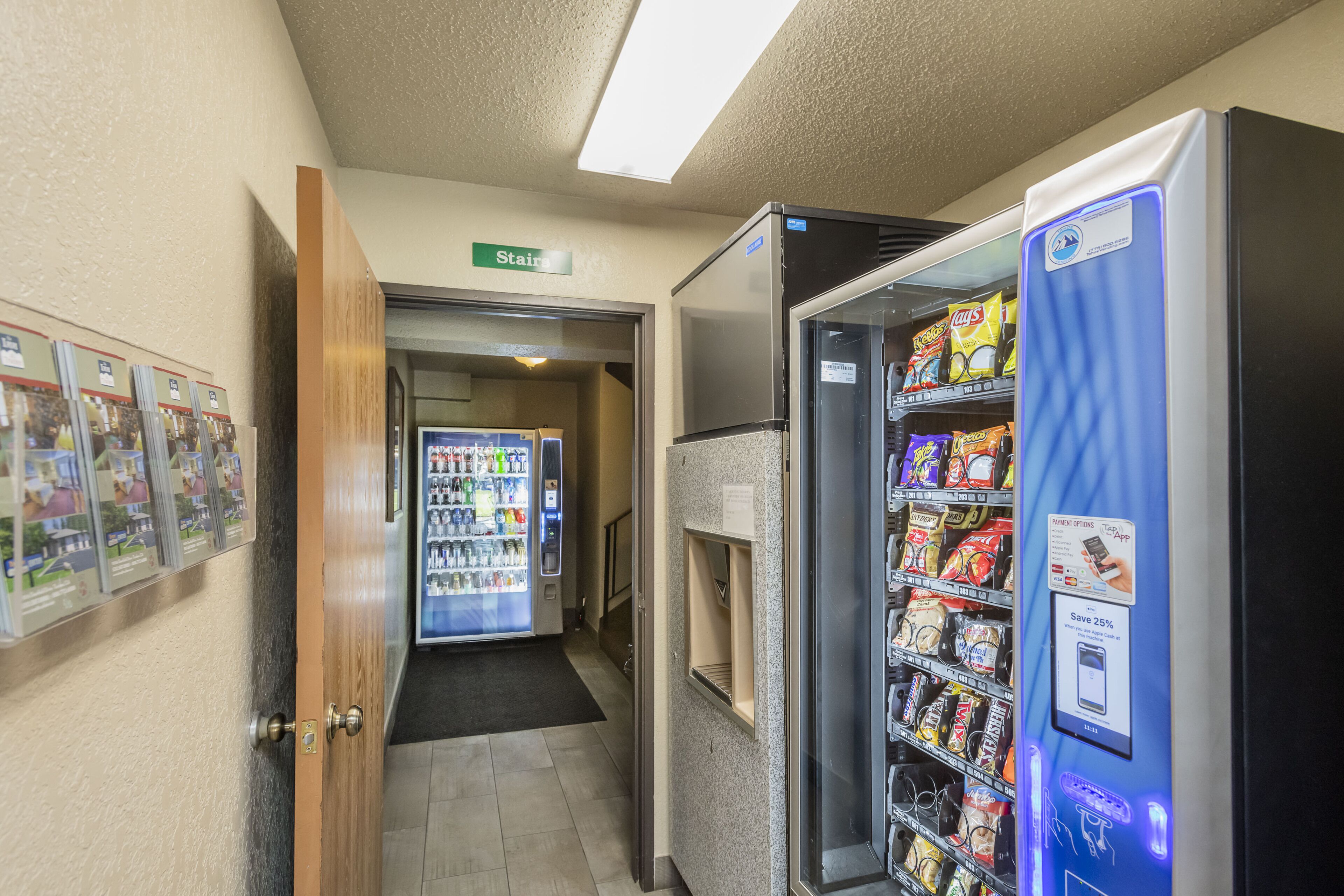 Un pasillo con una máquina expendedora llena de aperitivos, un refrigerador y un dispensador de agua.