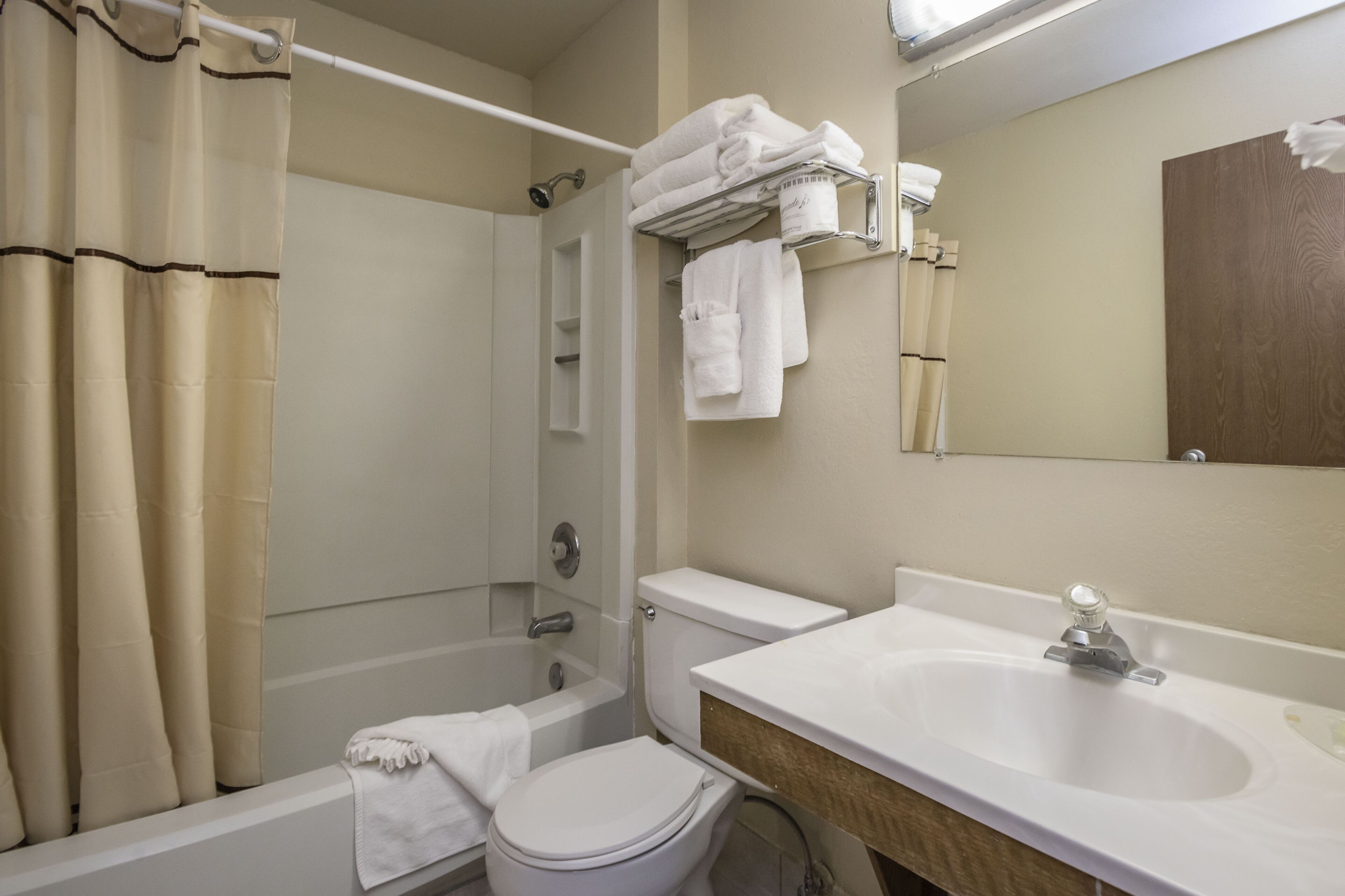 A bathroom with a bathtub, toilet, sink, and a towel rack with folded towels.