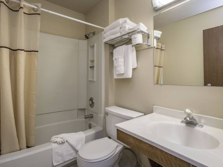 A bathroom with a bathtub, toilet, sink, and a towel rack with folded towels.
