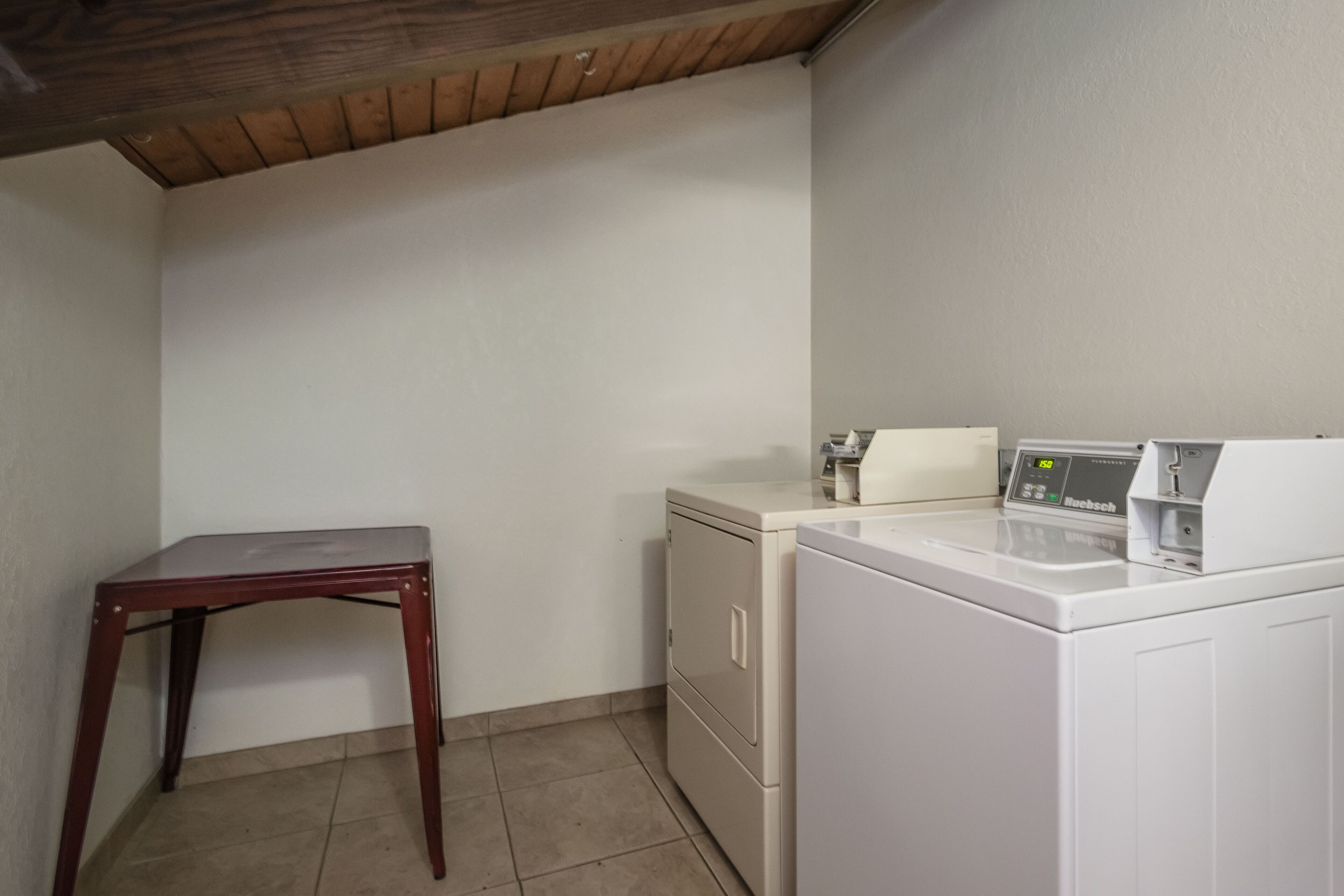 Uma lavanderia com máquina de lavar, secadora e uma mesa de madeira.
