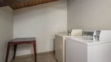 Un lavadero con lavadora, secadora y una mesa de madera.