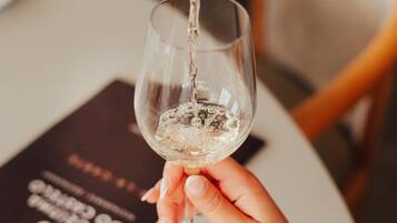 A hand holding a wine glass with a bottle pouring wine into it.