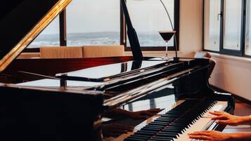 A grand piano in a room with large windows, a lamp, and a book on the piano.
