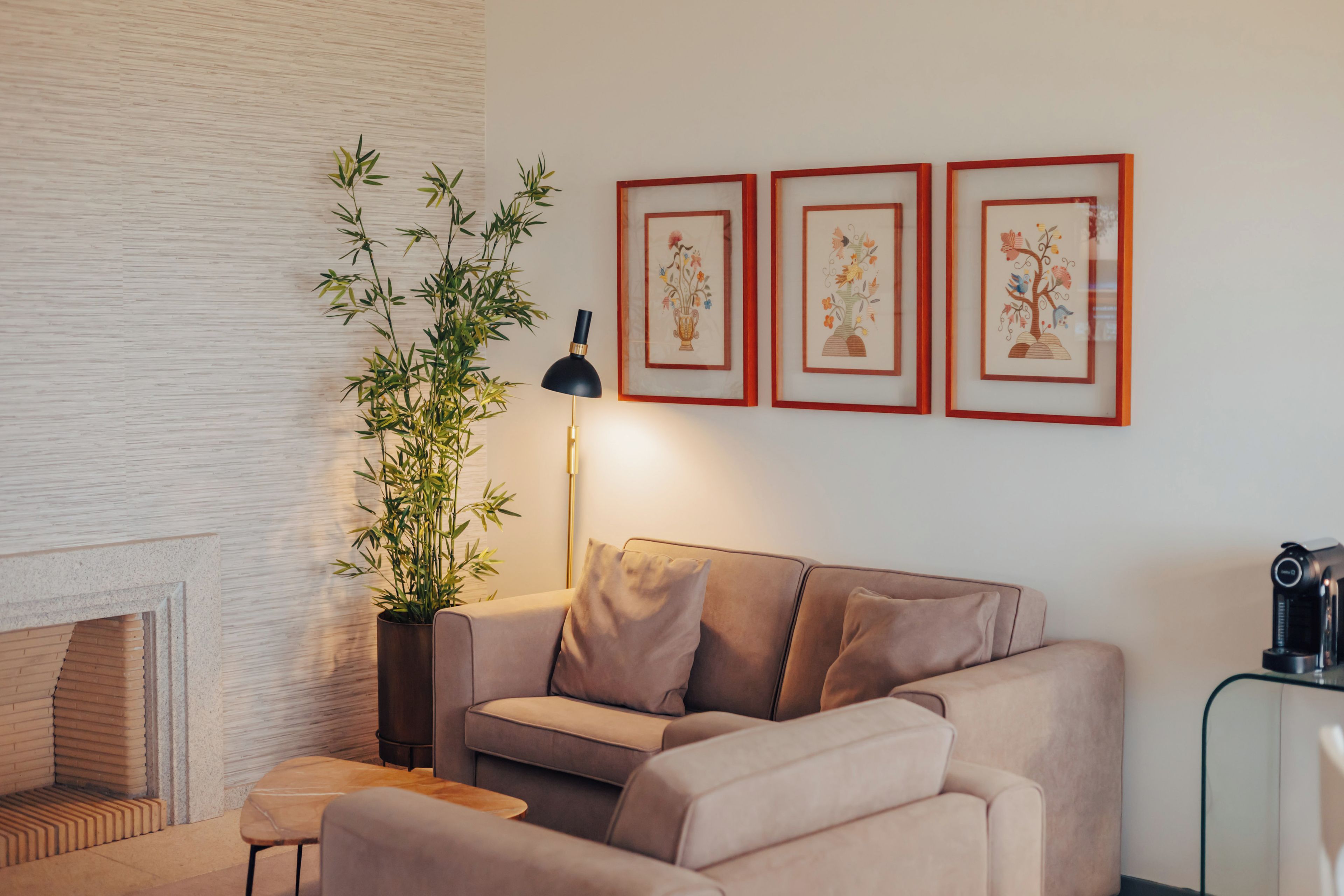 Ein modernes Wohnzimmer mit einer Couch, einem Beistelltisch, einer Lampe, einem Blumentopf und drei gerahmten Kunstwerken an der Wand.