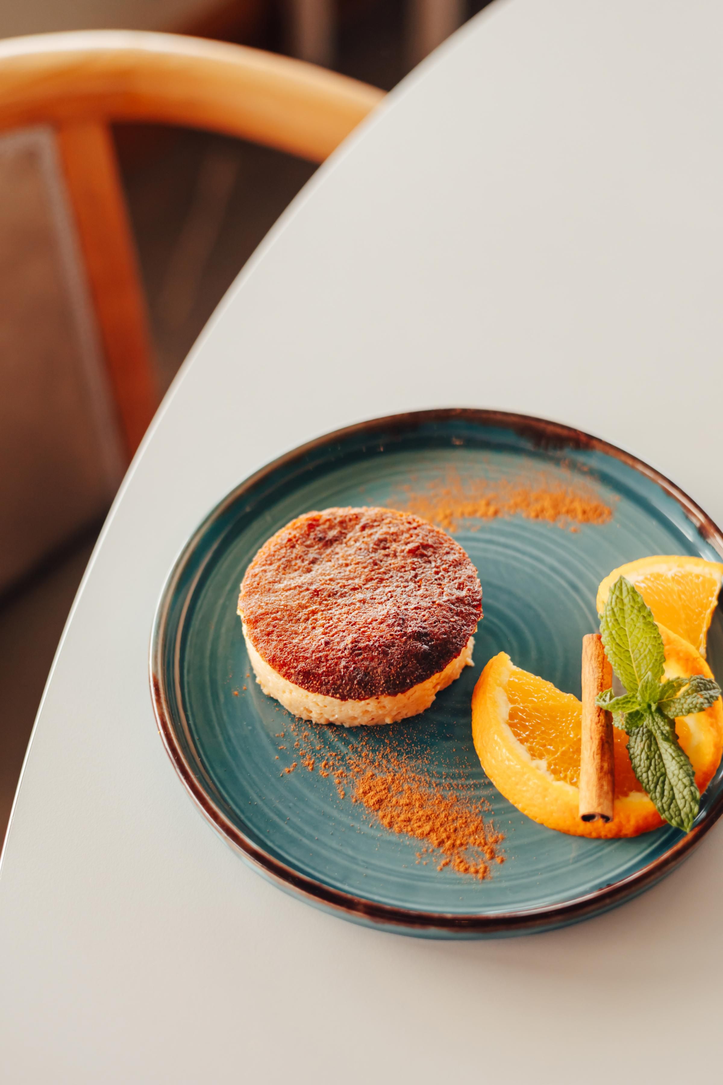 A dessert on a plate with a cinnamon stick and mint leaves.