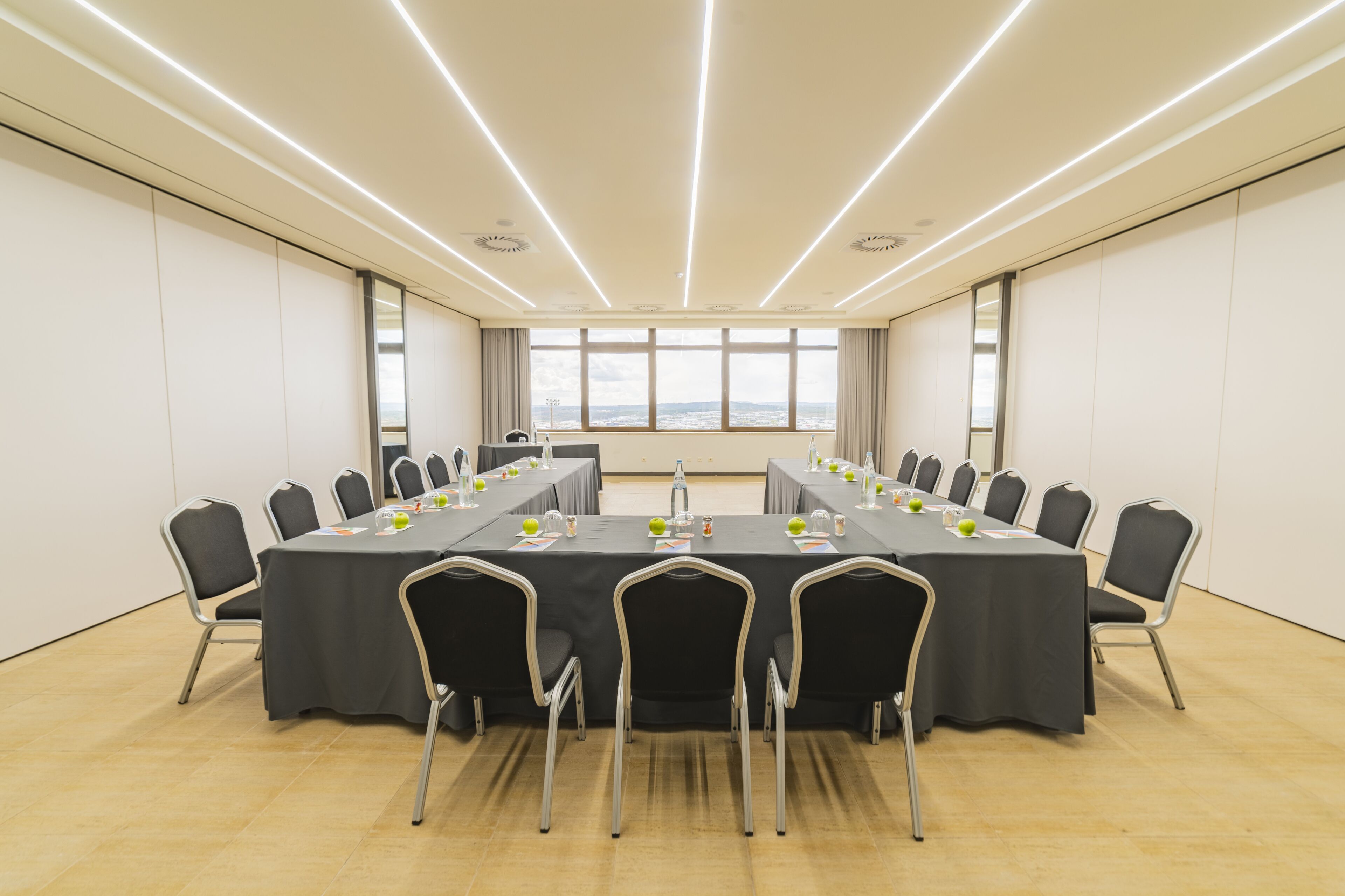Un salón de conferencias con una larga mesa, sillas y vistas a través de las ventanas.
