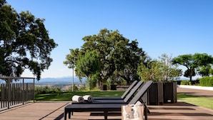 A sun lounger with towels, a bag, and a view of a green landscape and mountains. - Melia Castelo Branco (Castelo Branco)