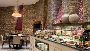 A restaurant with a brick wall, a round dining table with chairs, and a buffet counter with various food items. - Catalonia El Pilar (Zaragoza)