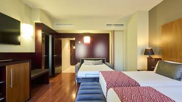 A hotel room with a bed, a desk, a TV, and a wardrobe.