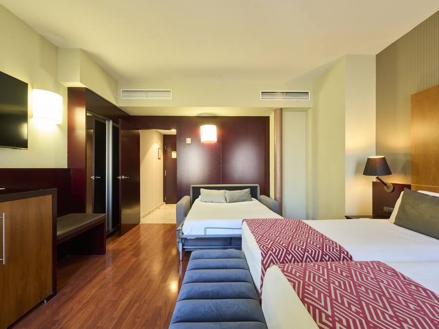A hotel room with a bed, a desk, a TV, and a wardrobe.