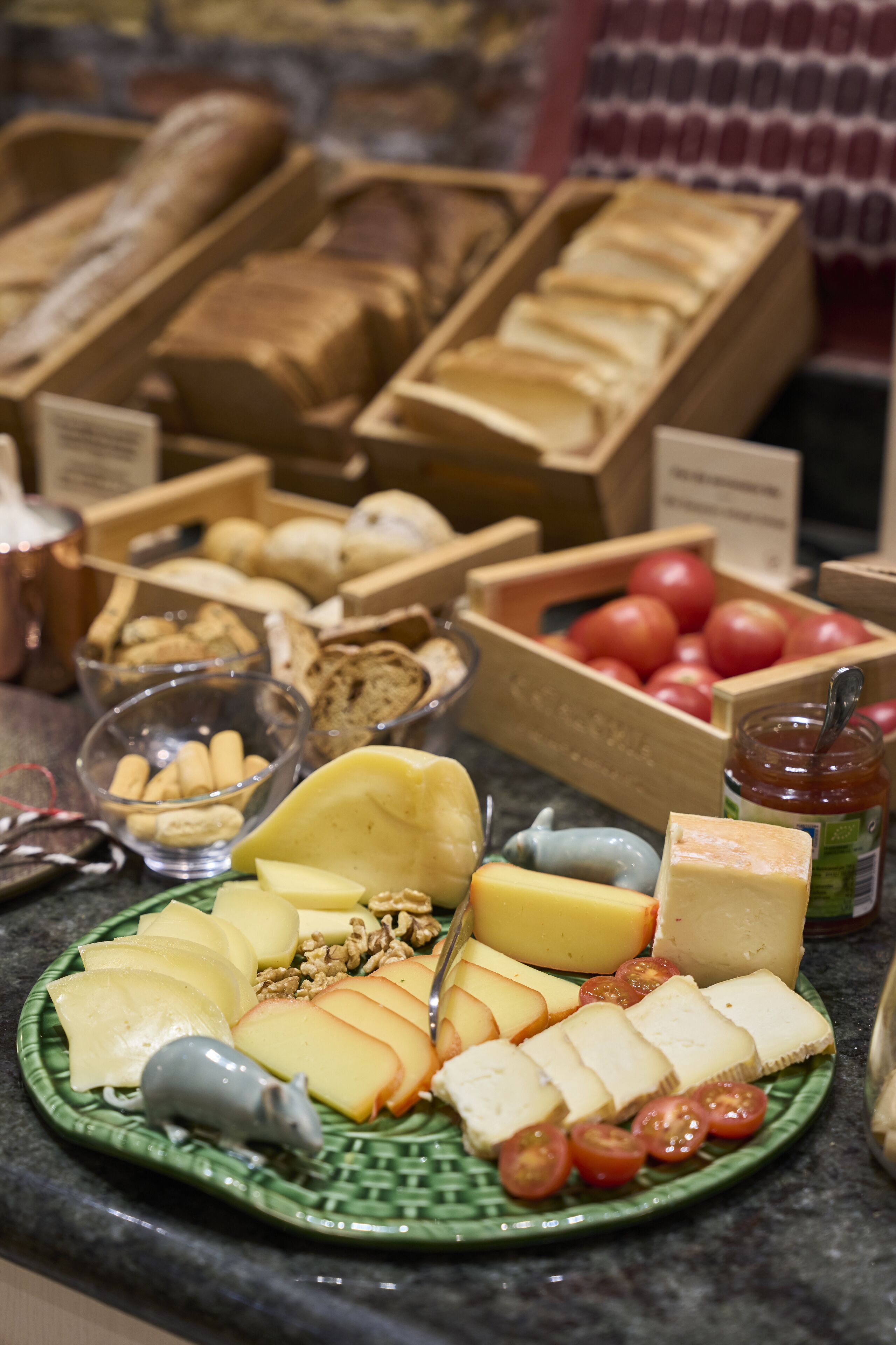 A breakfast buffet with various cheeses, fruits, and pastries.