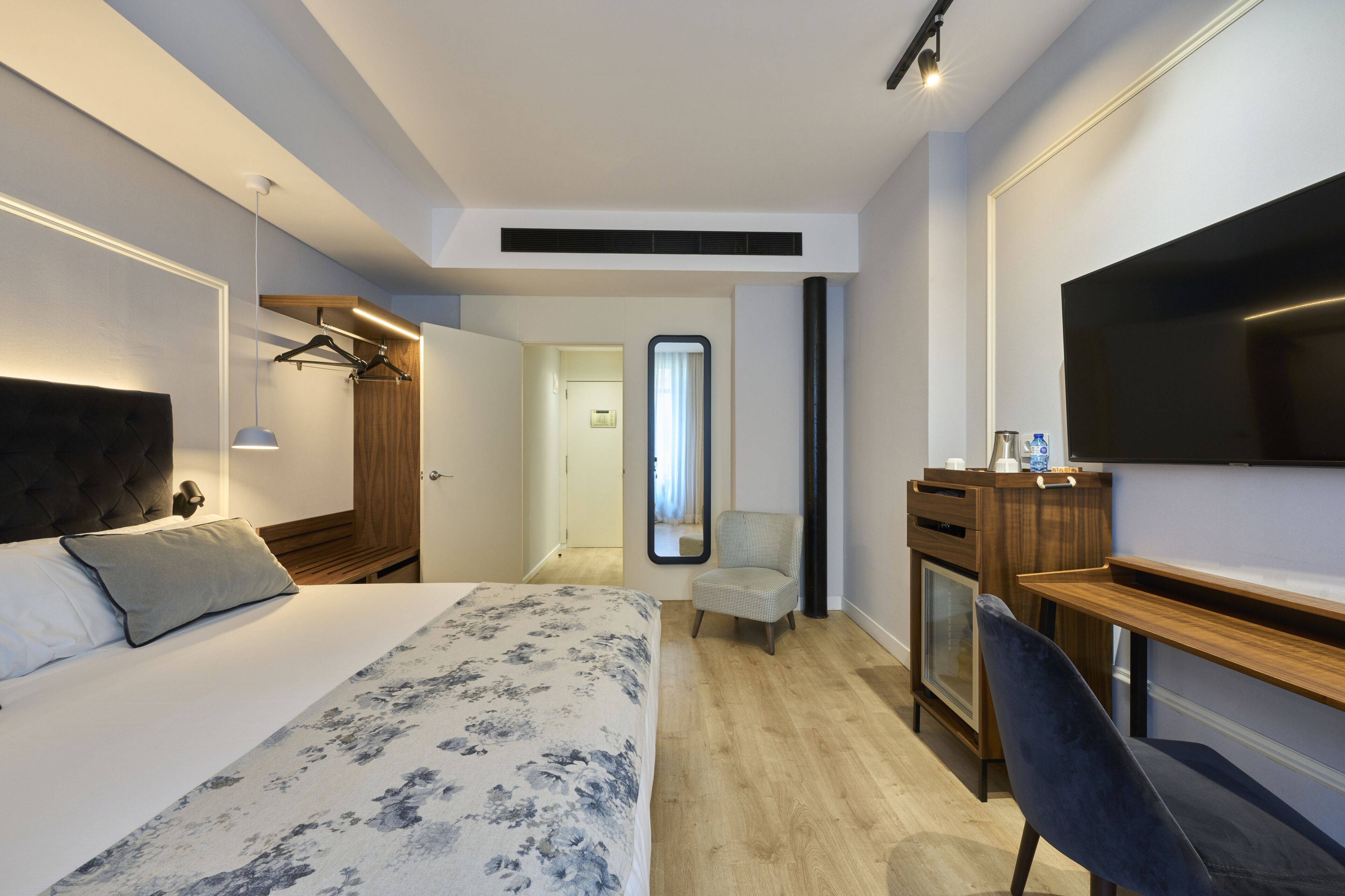 Una habitación de hotel con una cama, un escritorio, una silla, un televisor y un armario.
