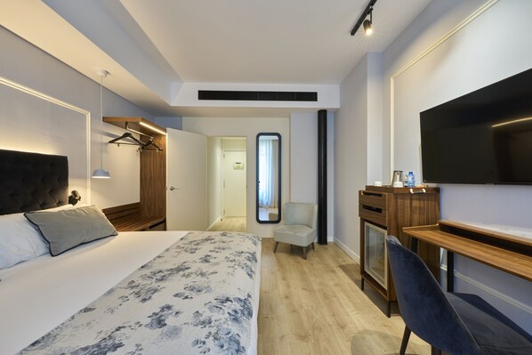Una habitación de hotel con una cama, un escritorio, una silla, un televisor y un armario.