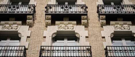 A building with multiple balconies, each with ornate wrought iron railings and decorative stonework.
