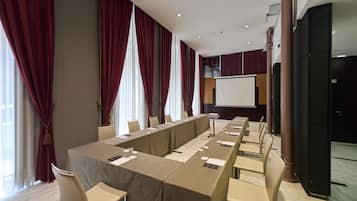 A conference room with a long table, chairs, a projector screen, and large windows with curtains.