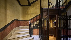 A grand staircase with marble steps and ornate black metal railings leading to a wooden door. - Catalonia El Pilar (Zaragoza)