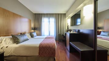 Habitación de hotel con dos camas, un escritorio, una silla, un espejo grande y una ventana con cortinas.