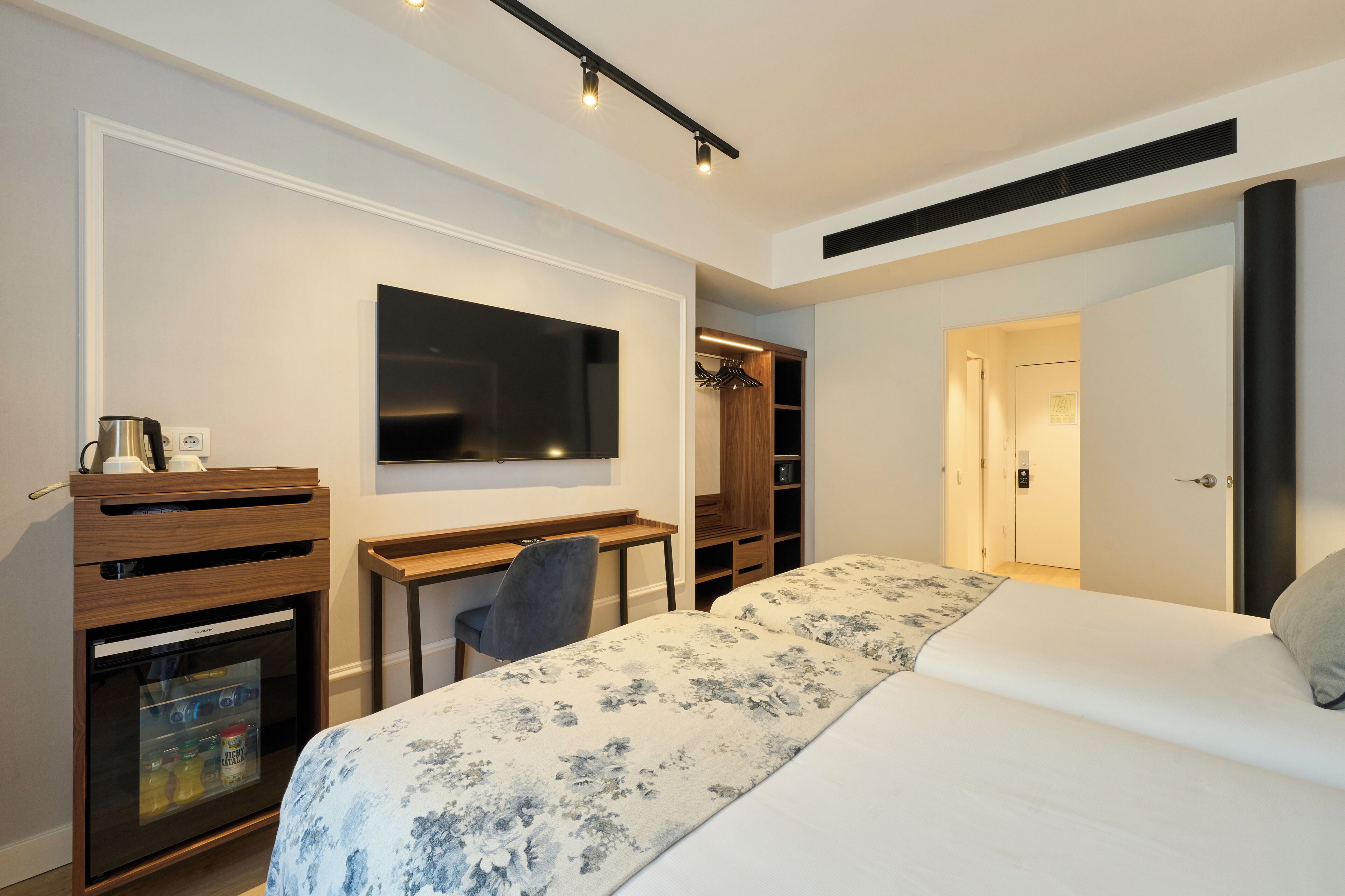 A bedroom with a bed, a desk, a TV, a wardrobe, and a closet.