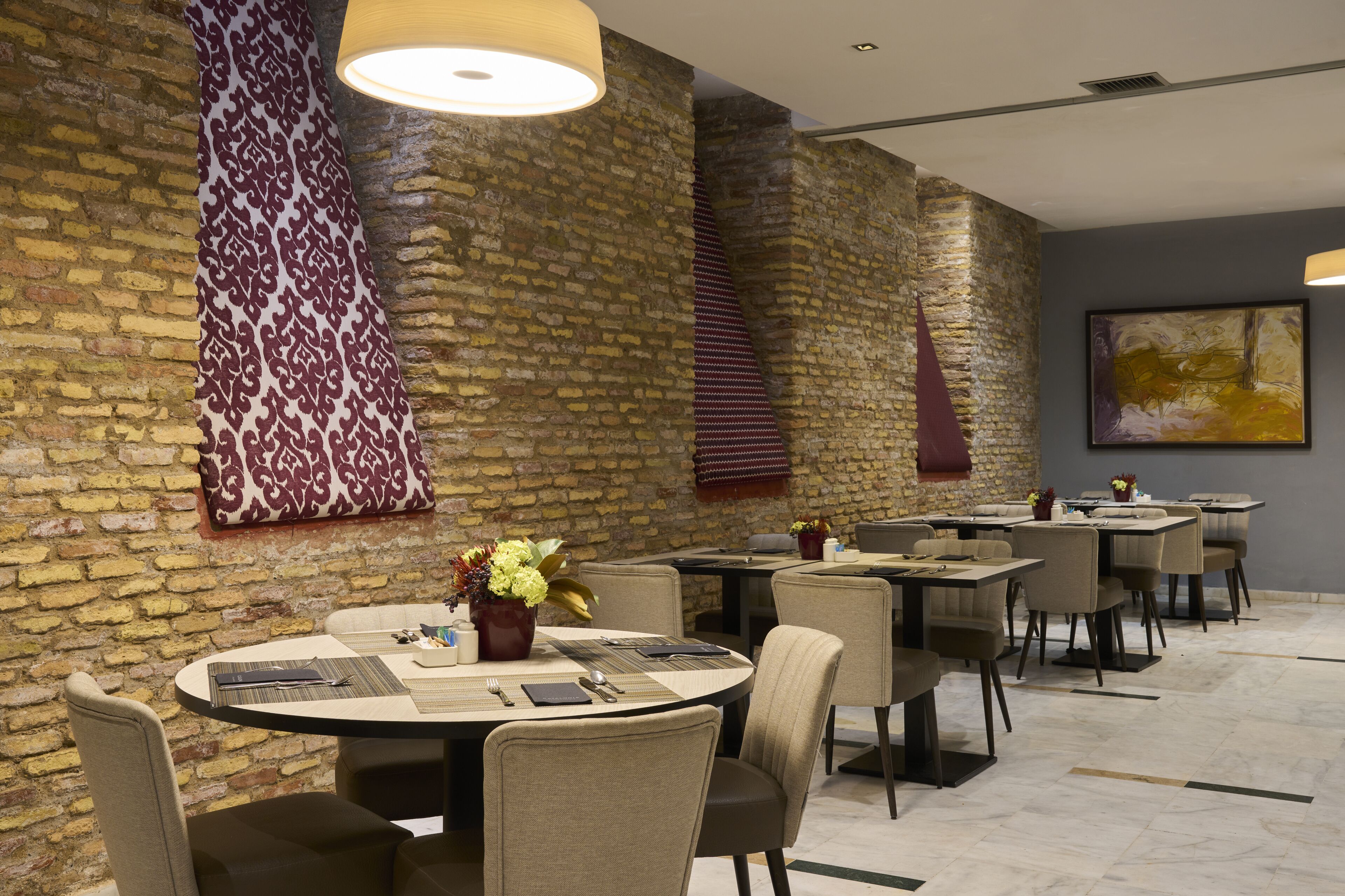 Un espace de restauration moderne avec des murs en briques, des tables rondes et des chaises.