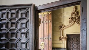 A wooden door with a geometric pattern and brass hardware. - Catalonia El Pilar (Zaragoza)