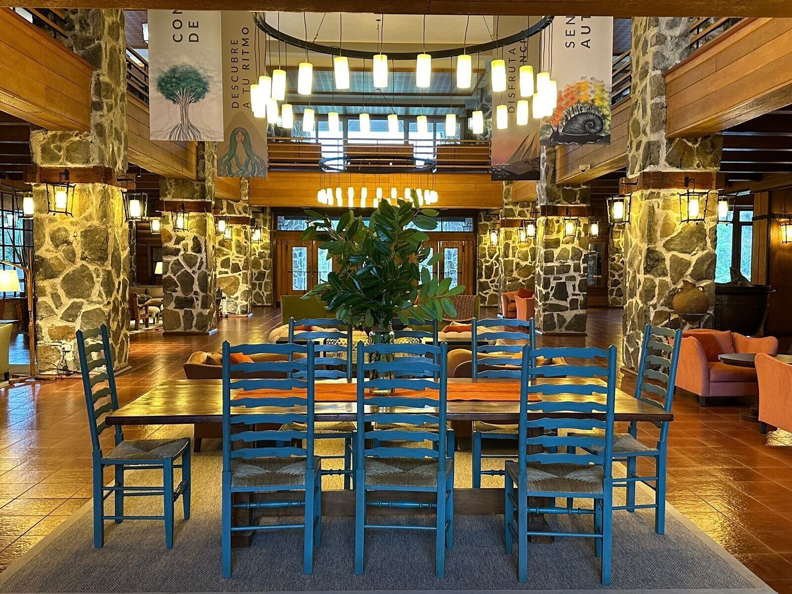 Eine geräumige Lobby mit einer zentralen Sitzgruppe, Steinwänden und hängenden Lampen.