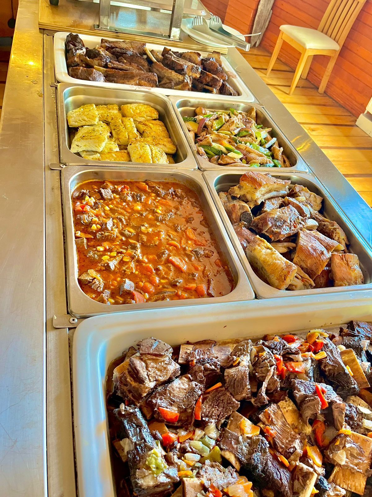 A buffet with various dishes including meats, vegetables, and a stew.