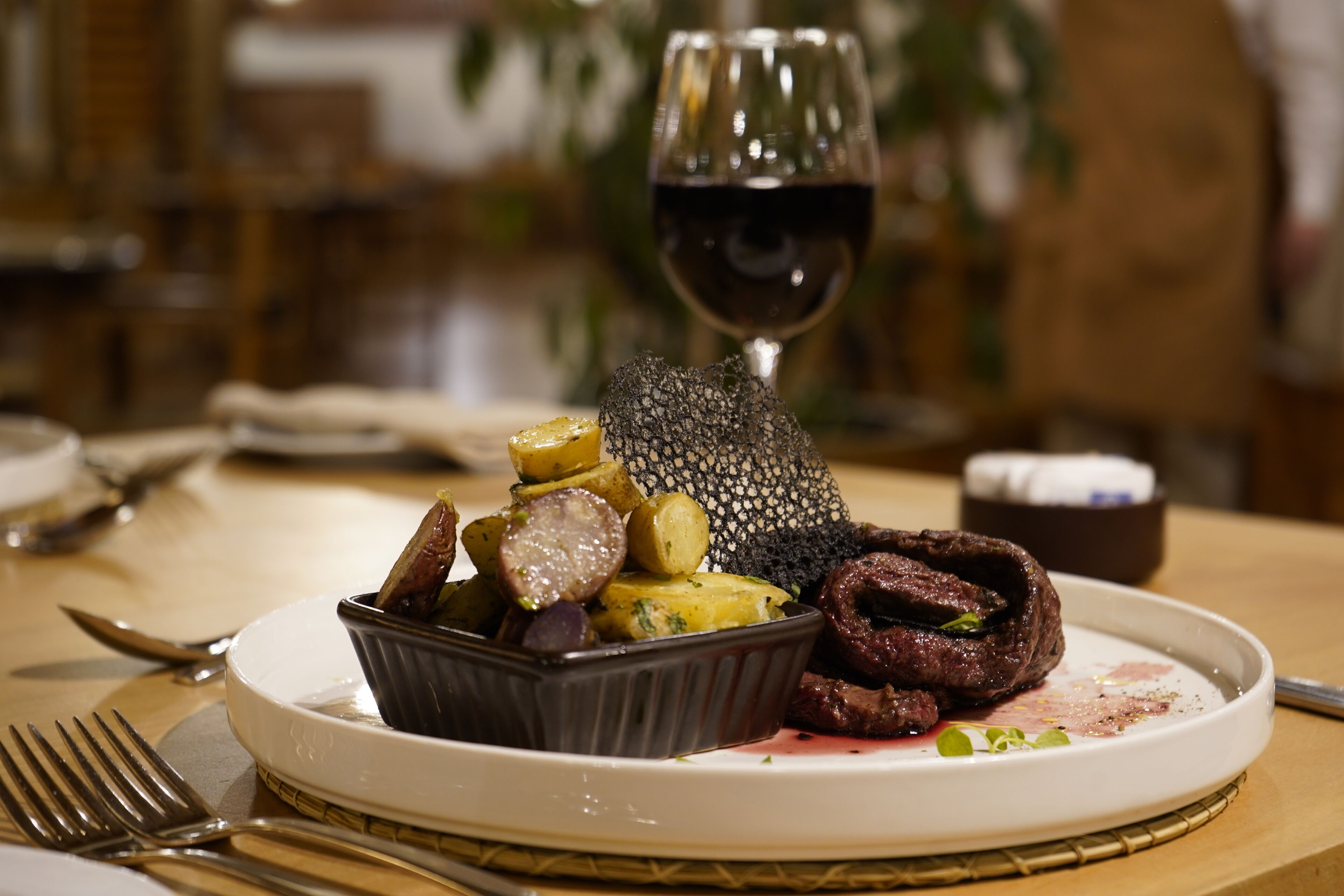 Un plato de comida con una copa de vino tinto.