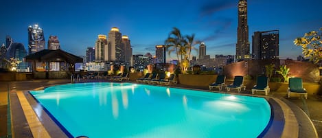 Una piscina al aire libre, sillones reclinables de piscina