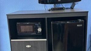 Eine schwarze Unterhaltungseinrichtung mit einem Flachbildfernseher, einer Mikrowelle und einem Kühlschrank.