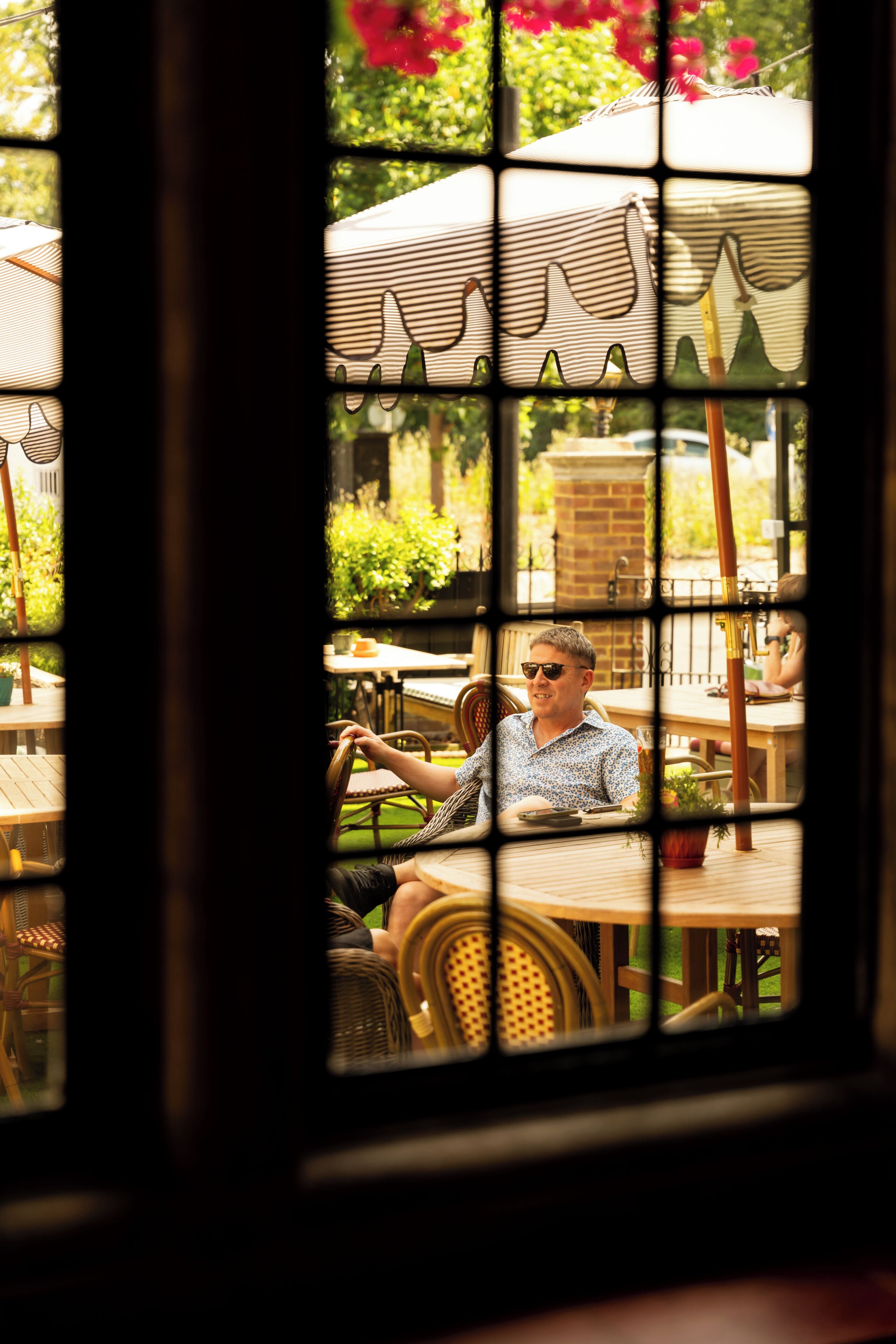 Una persona sentada a una mesa con vistas a través de una ventana con diseño a rayas.