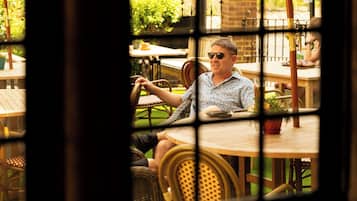 Una persona sentada a una mesa con vistas a través de una ventana con diseño a rayas.