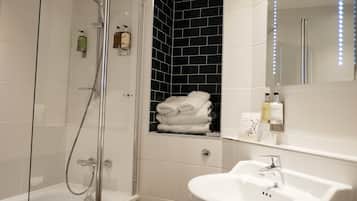 A modern bathroom with a glass-enclosed shower, a white sink, and a towel rack with folded towels.