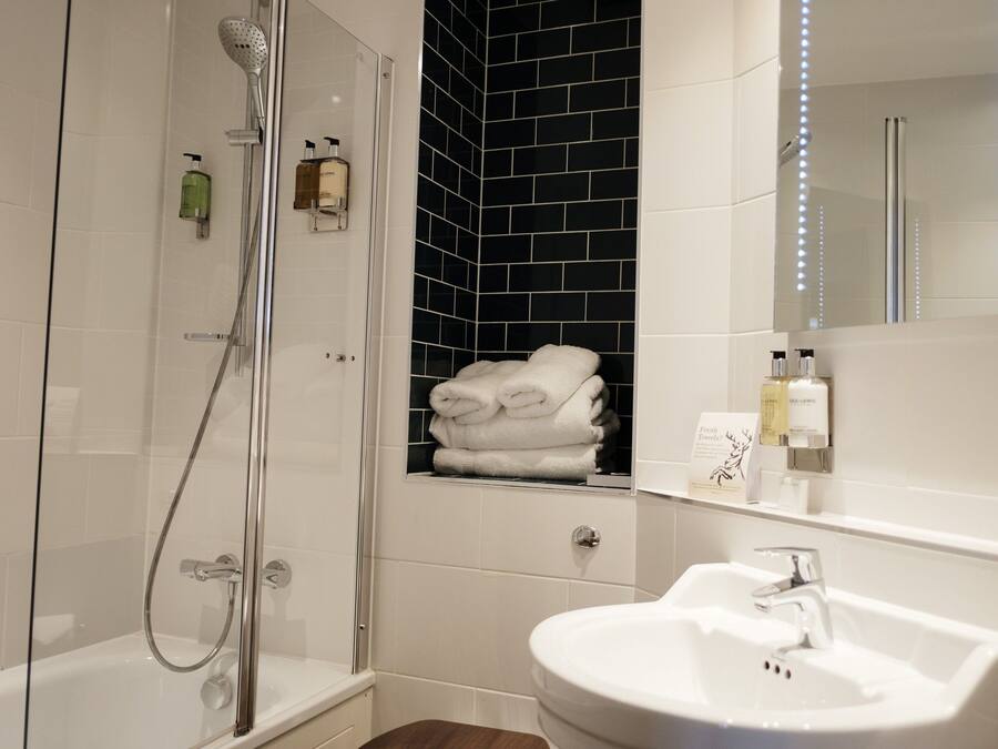 A modern bathroom with a glass-enclosed shower, a white sink, and a towel rack with folded towels.