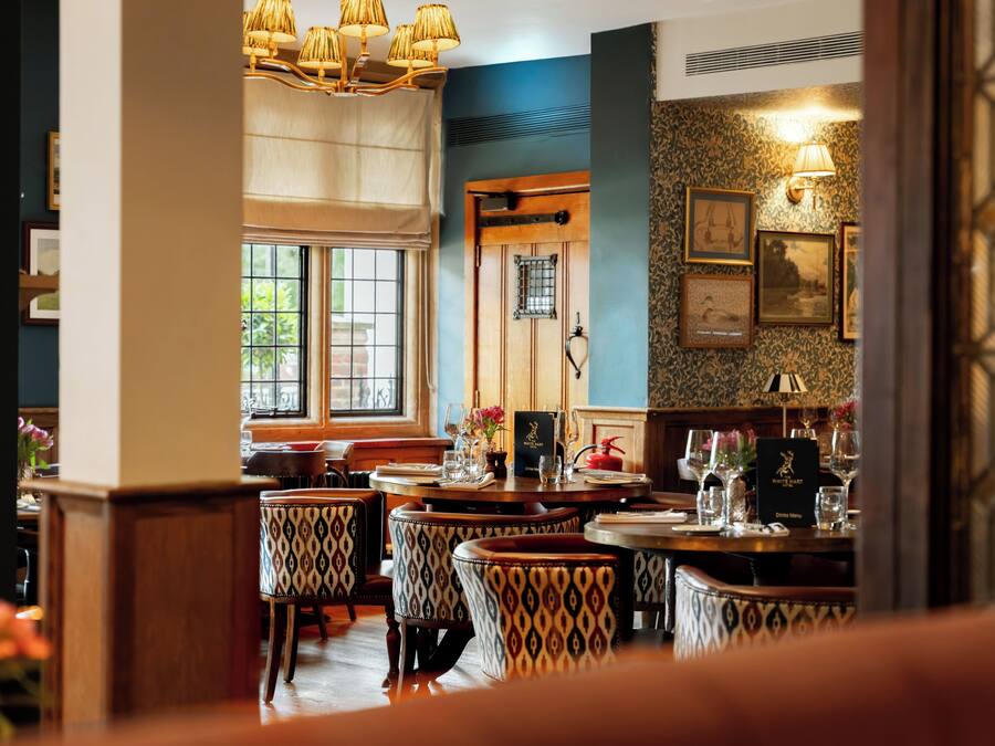 L’intérieur d’un restaurant avec des tables en bois, des chaises à motifs et un mur d’accent bleu.