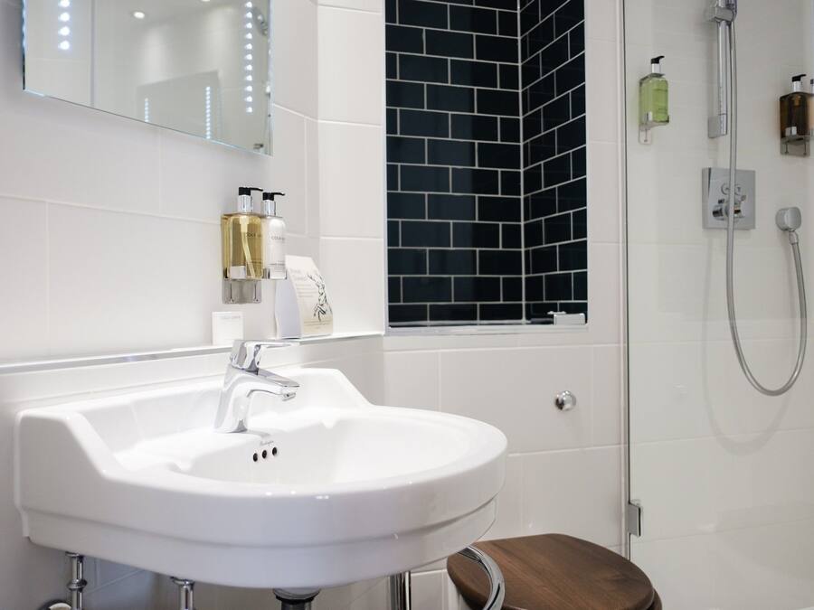 A bathroom with a white sink, a mirror, and a shower area.