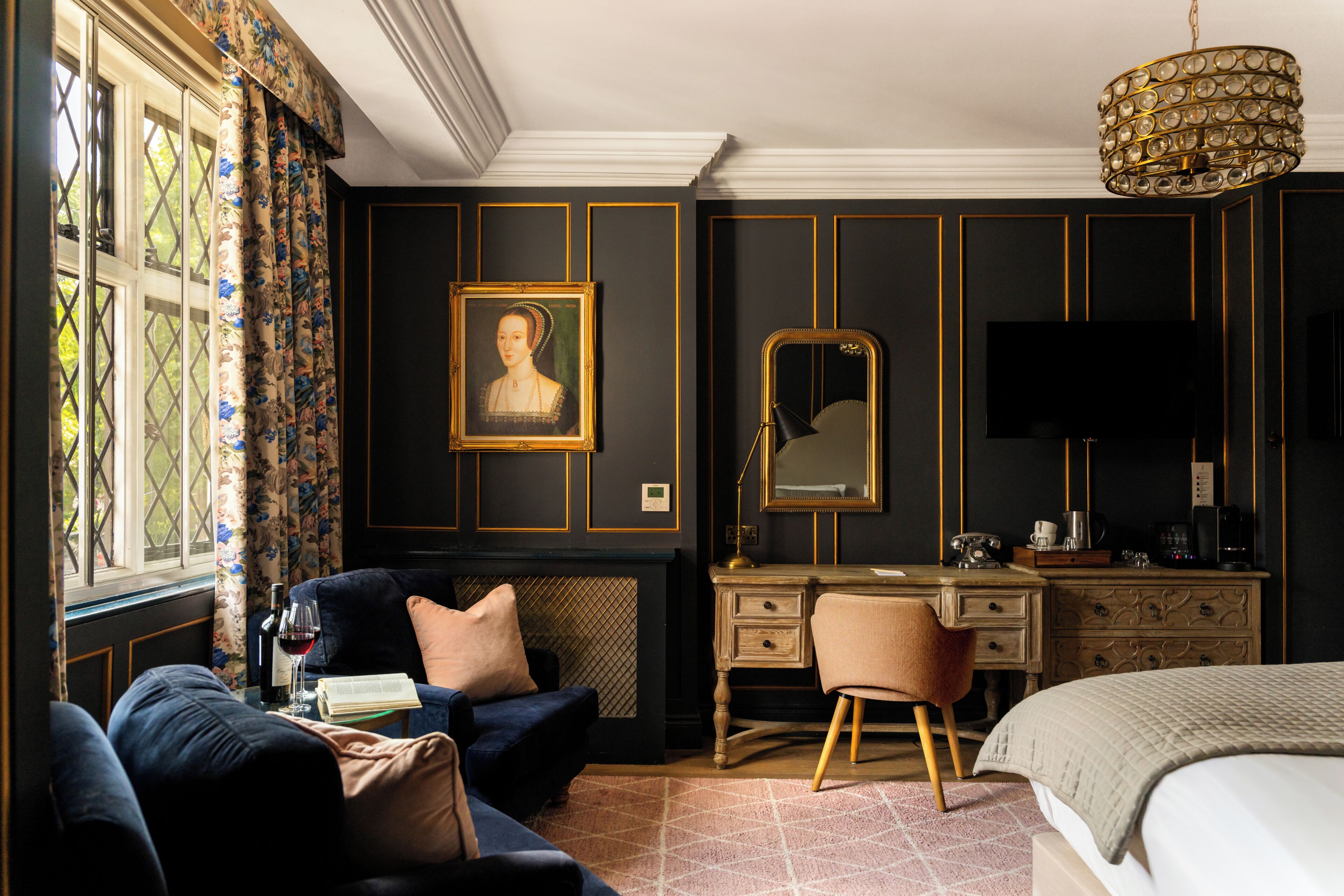Une pièce comprenant un lit, un bureau, une chaise, une commode, un miroir, un tableau et une fenêtre avec des rideaux.