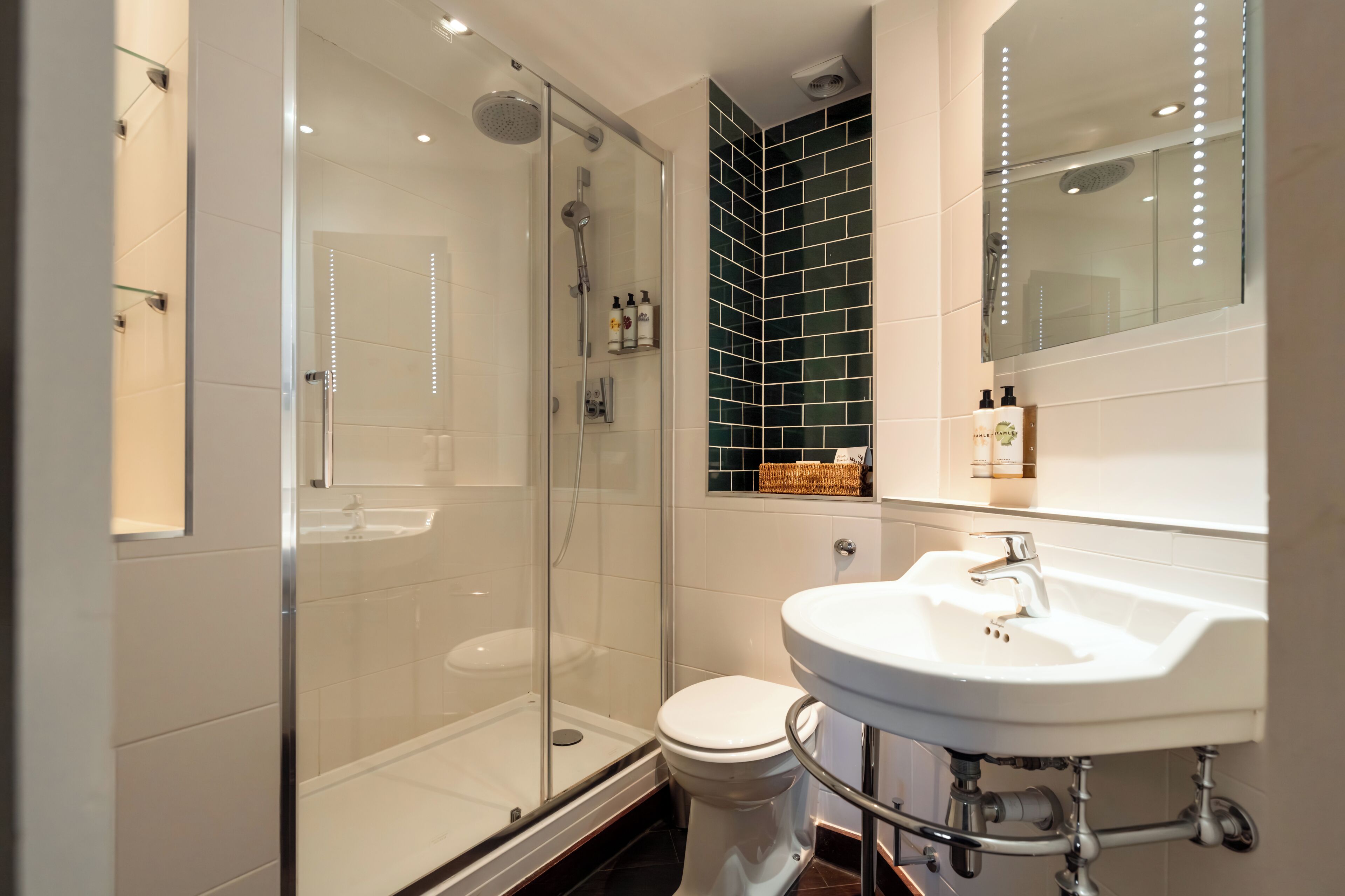 A modern bathroom with a glass-enclosed shower, a white sink, and a black-tiled accent wall.