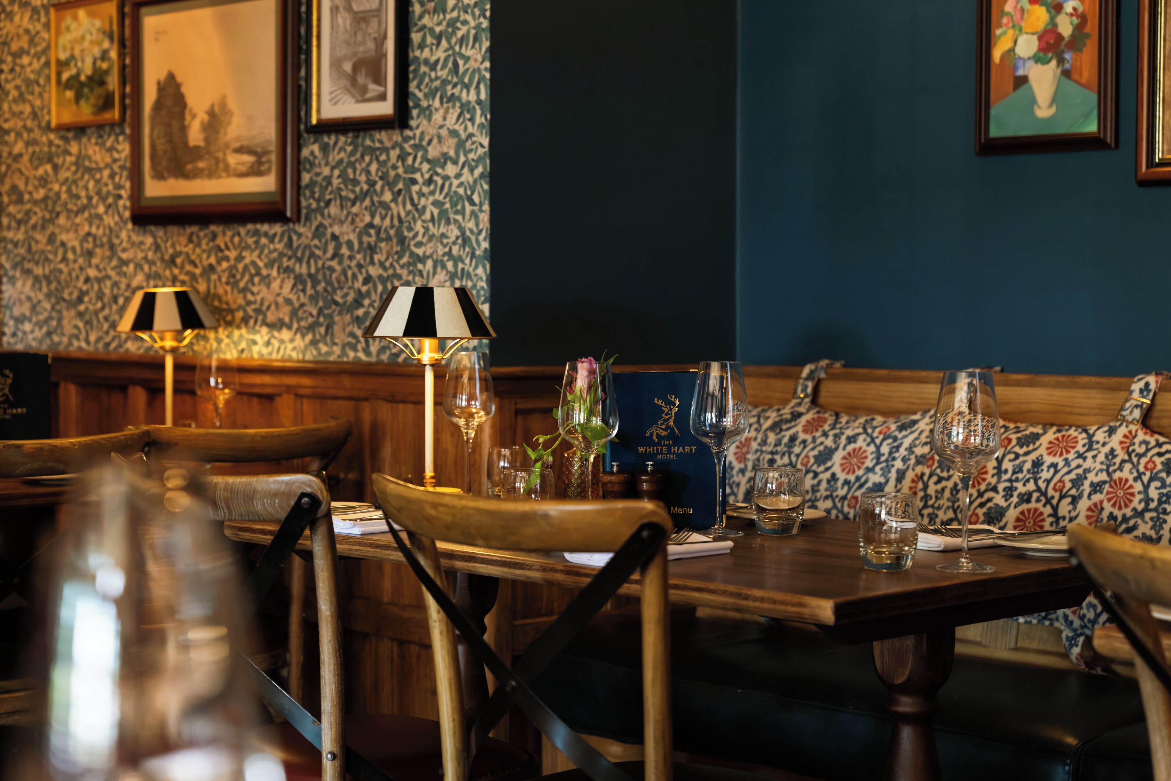 A dining area with wooden furniture, a table set for two, and a menu on the table.